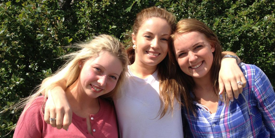 Tre smilende jenter i videregående skole-alder, foto